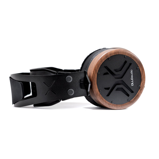 A pair of OLLO Audio X2 over-ear headphones with a black leather strap and headband, featuring a circular wooden-rimmed earcup with a black speaker grille.