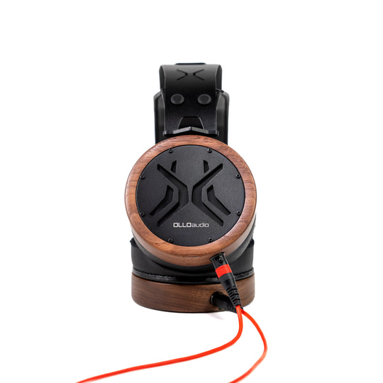 A pair of OLLO Audio over-ear headphones featuring a circular wooden-grain outer cup with a black center and logo, shown on a white background with a red cable.