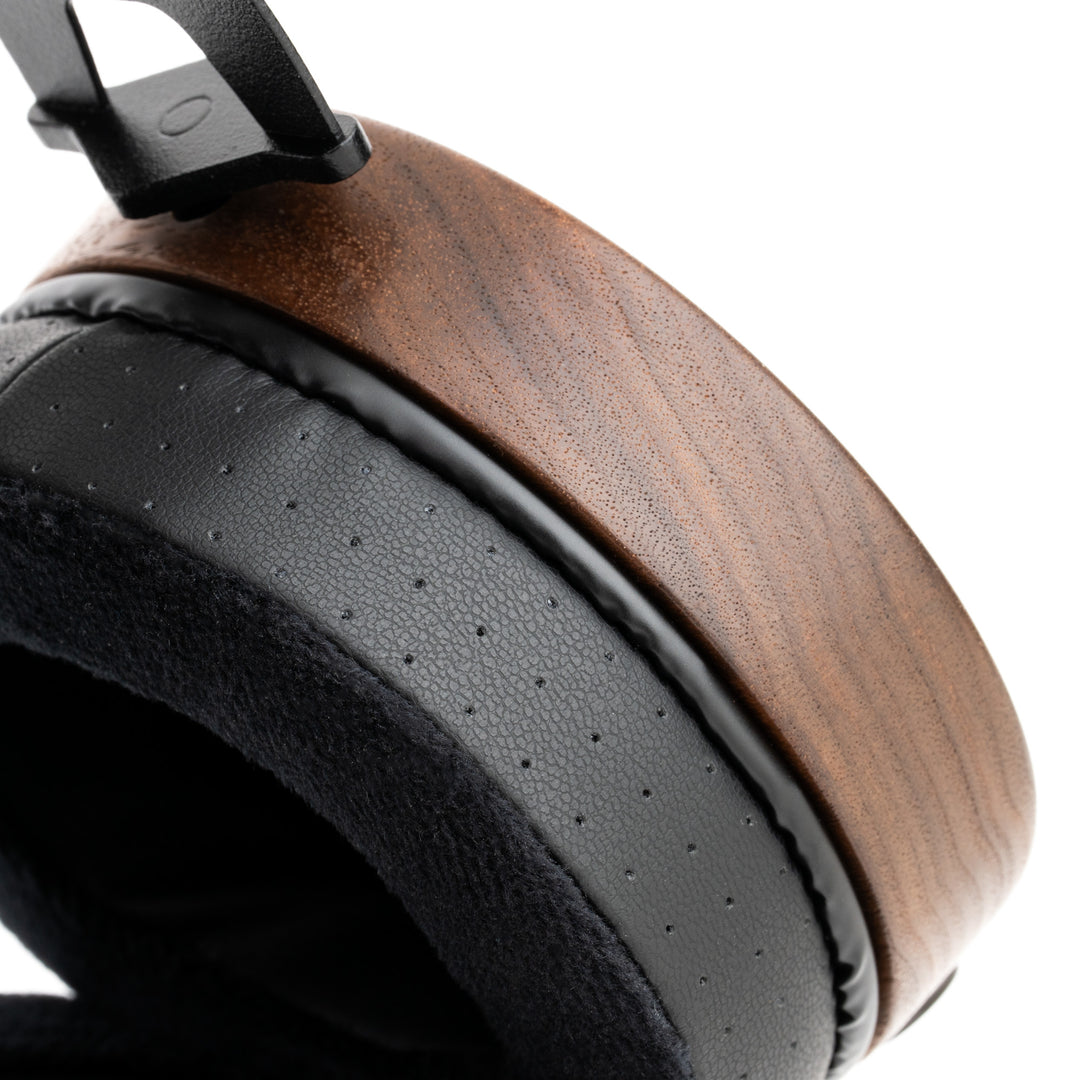 Close-up of a large over-ear headphone earcup with a brown wood-grain outer shell and a black perforated foam headband.