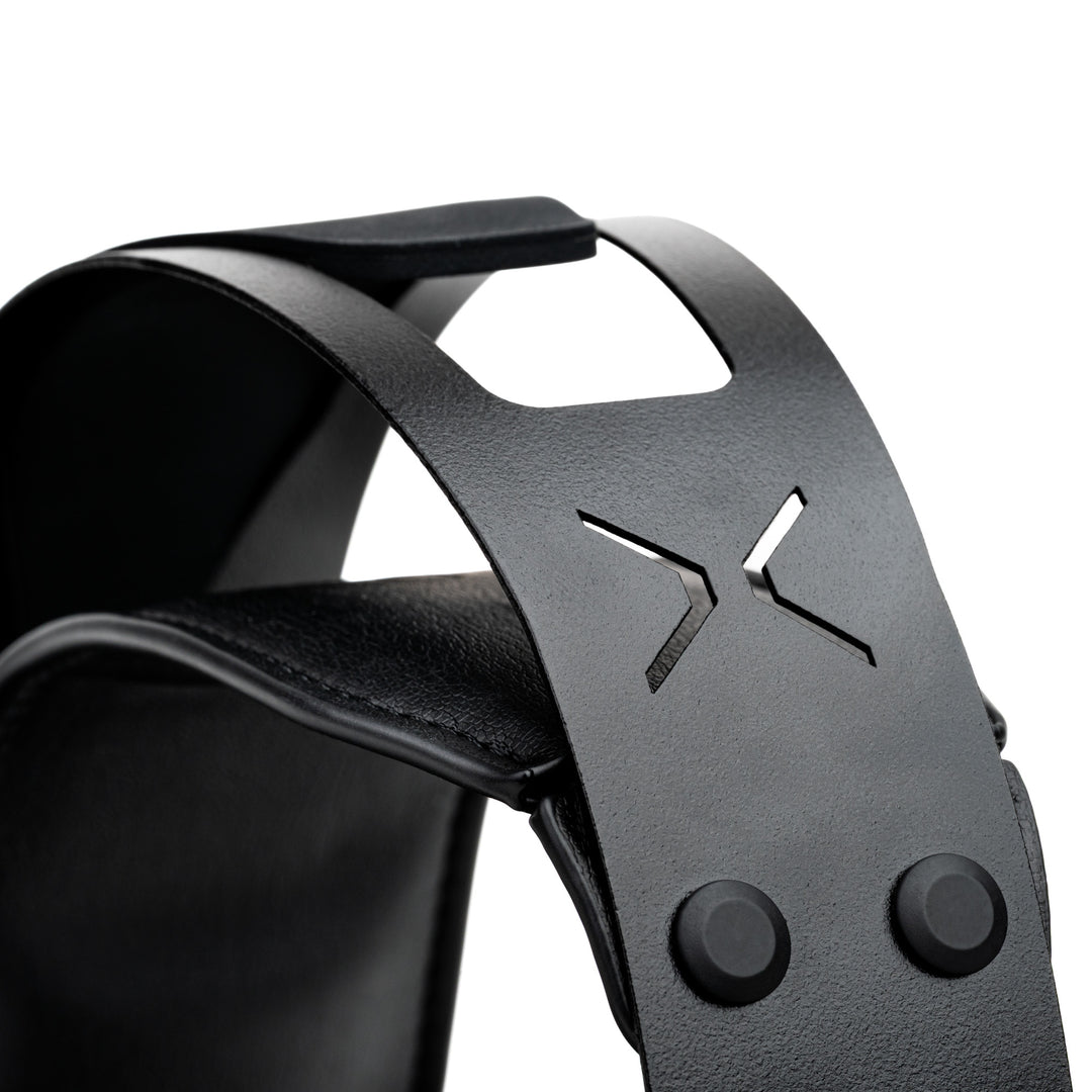 Close-up of a black leather headband with a textured finish, featuring a cutout logo and two snap buttons on a white background.